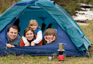 a happy family peeks from their tent